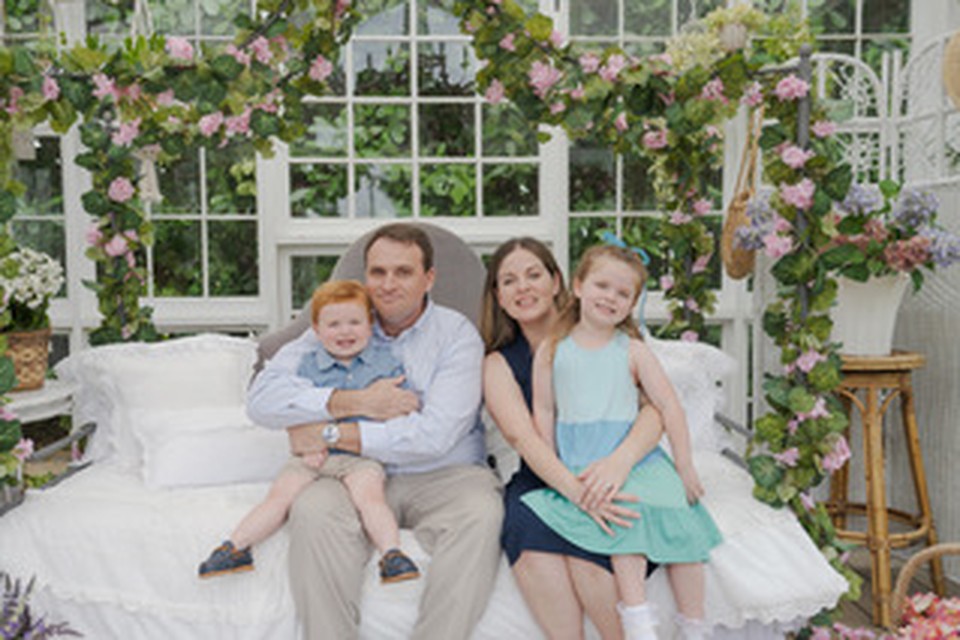 Katie with her family in a greenhouse setting.